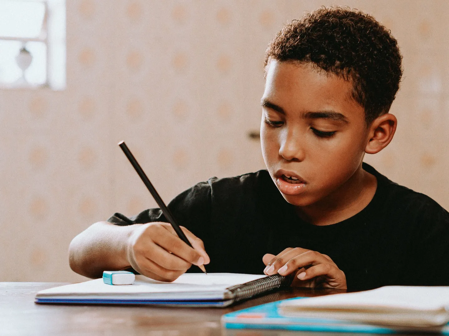 Child writing on book in classroom